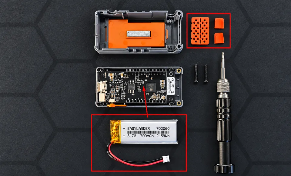 Opened case, the board, the orange parts and the battery laid out